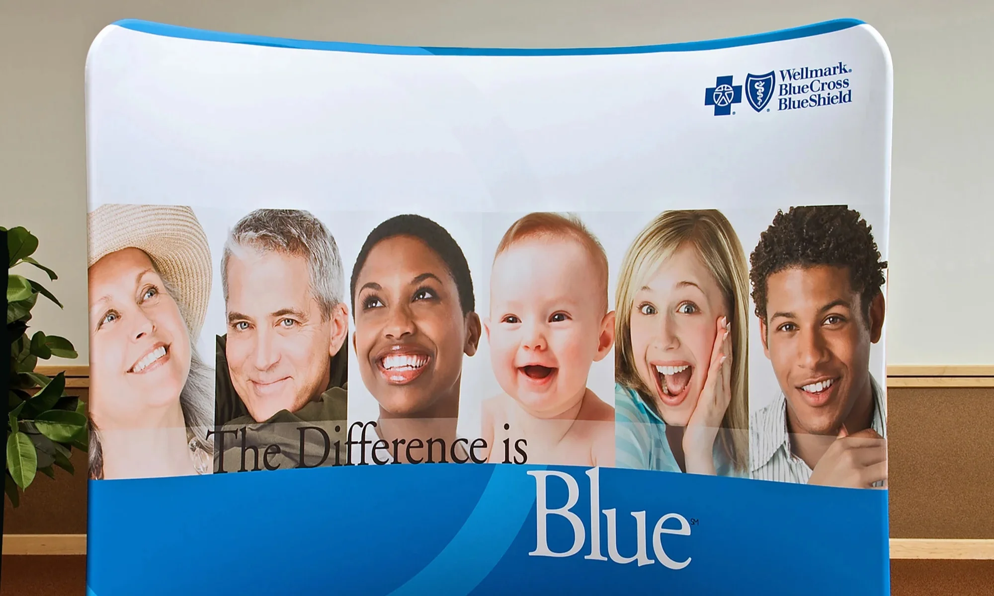 Wellmark Blue Cross and Blue Shield curved fabric backwall with smiling portraits and The Difference is Blue graphic by Suncoast Displays