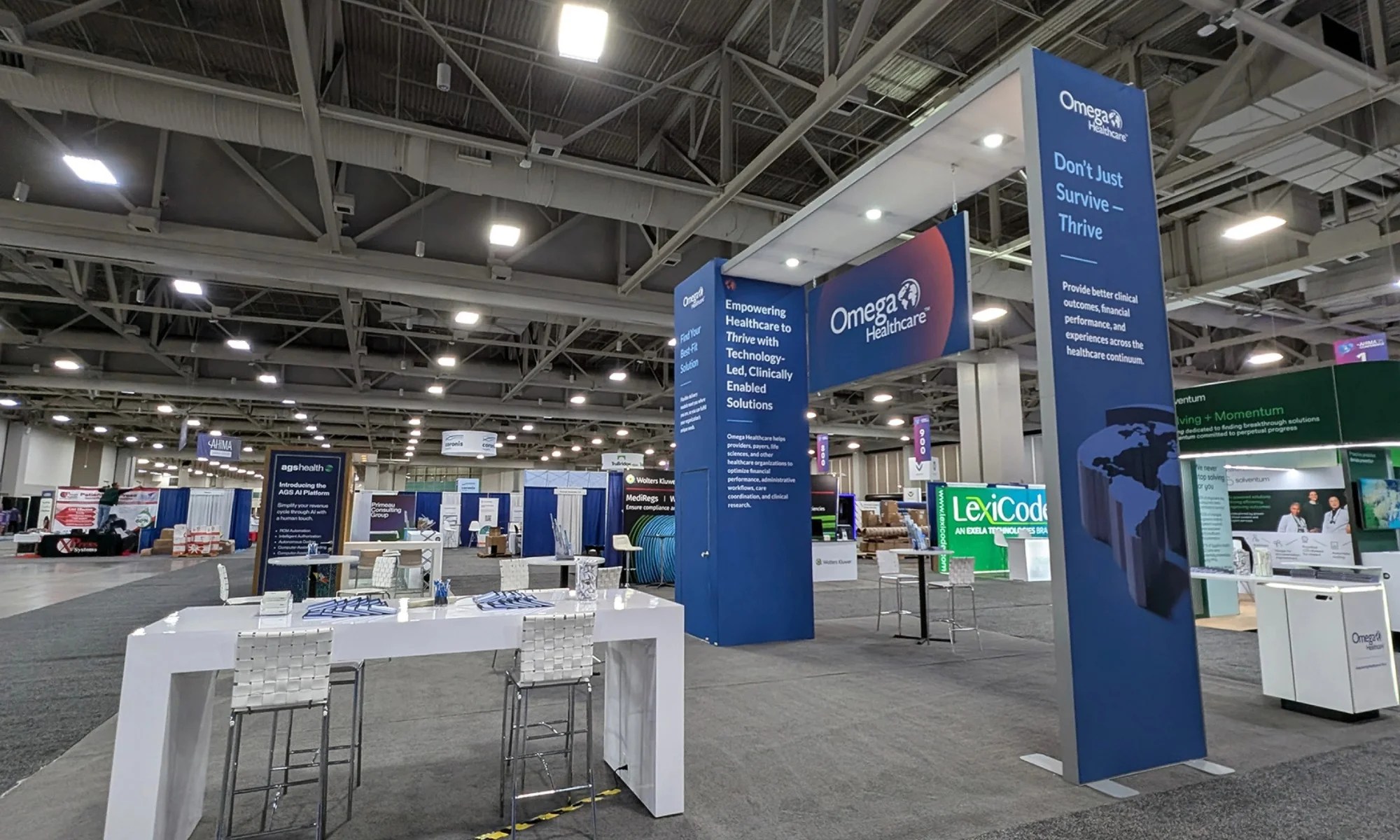 Omega Healthcare trade show exhibit with tall branded towers, header sign, and collaborative demo counters by Suncoast Displays