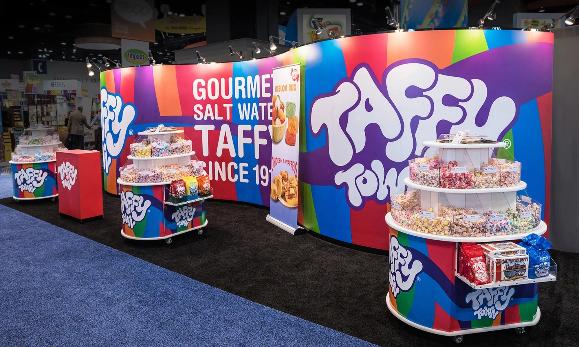 Taffy Town custom trade show booth with colorful curved backwall and candy display carts by Suncoast Displays